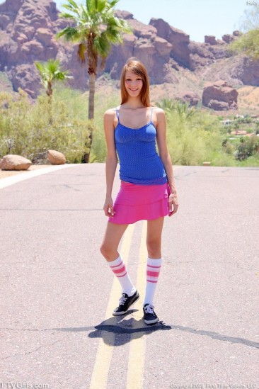 Юная девочка Holly Michaels в голубом топе и розовой юбке кратковременно обнажает сиськи и киску у дороги
